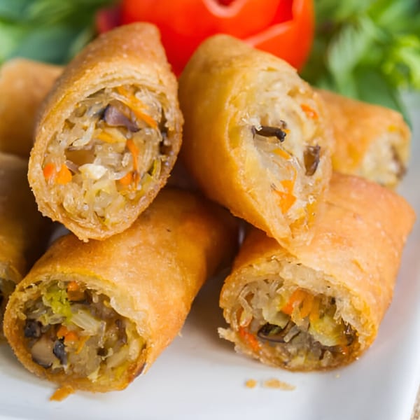 Close-up of golden-brown spring rolls, cut open to reveal a filling of vegetables and mushrooms.